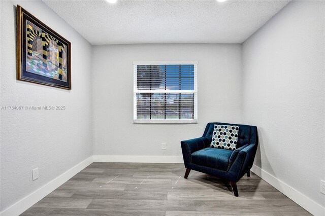 living area with baseboards, recessed lighting, wood finished floors, and a textured ceiling