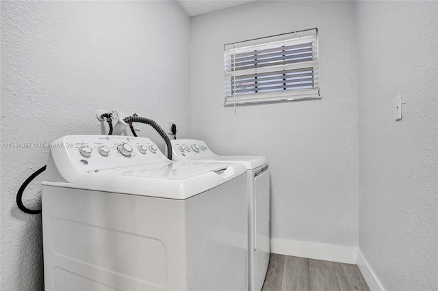 laundry room with laundry area, wood finished floors, baseboards, and washing machine and dryer