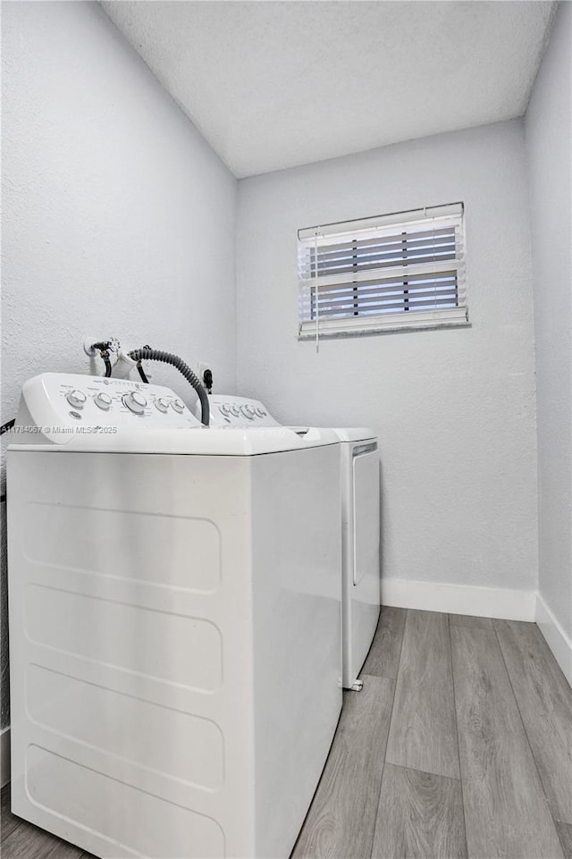 laundry area with baseboards, wood finished floors, washer and dryer, and laundry area