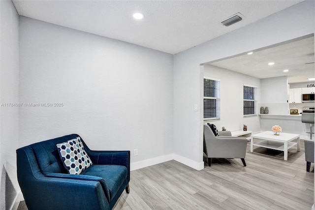 living area featuring recessed lighting, visible vents, light wood-type flooring, and baseboards
