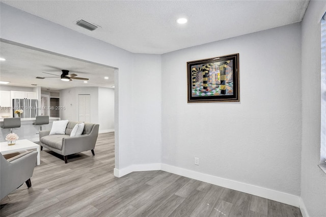 living room featuring visible vents, baseboards, and light wood finished floors