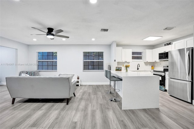 kitchen with light countertops, visible vents, a breakfast bar area, ceiling fan, and appliances with stainless steel finishes