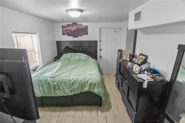 bedroom with light wood-style floors and visible vents