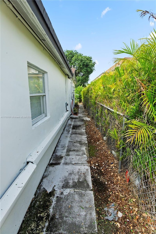 view of side of home featuring stucco siding and fence