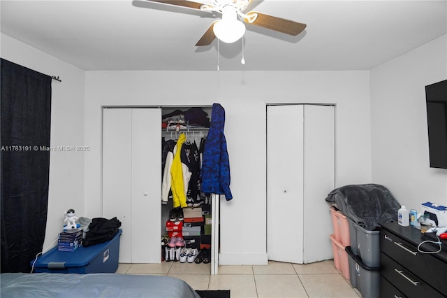 bedroom featuring light tile patterned floors, ceiling fan, and multiple closets