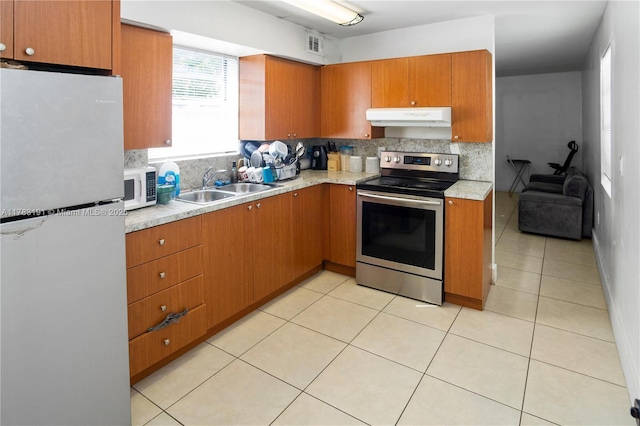 kitchen featuring white microwave, freestanding refrigerator, stainless steel electric stove, under cabinet range hood, and a sink