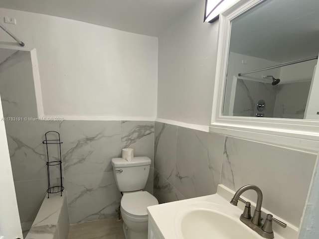 full bathroom featuring a shower, vanity, a wainscoted wall, and toilet
