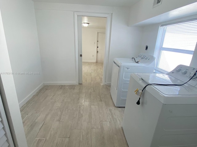 clothes washing area with baseboards, light wood-style floors, visible vents, laundry area, and washer and dryer