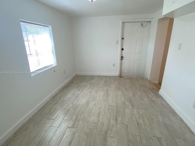 empty room with light wood-type flooring and baseboards