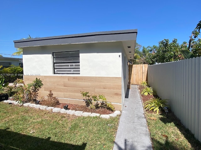 view of side of home with stucco siding and fence