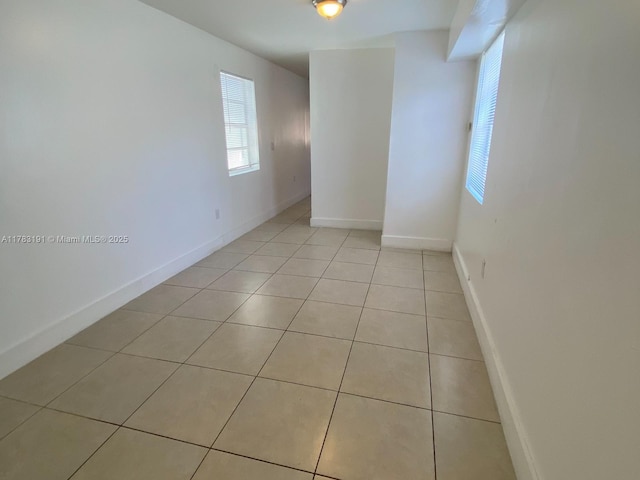 spare room with light tile patterned floors and baseboards