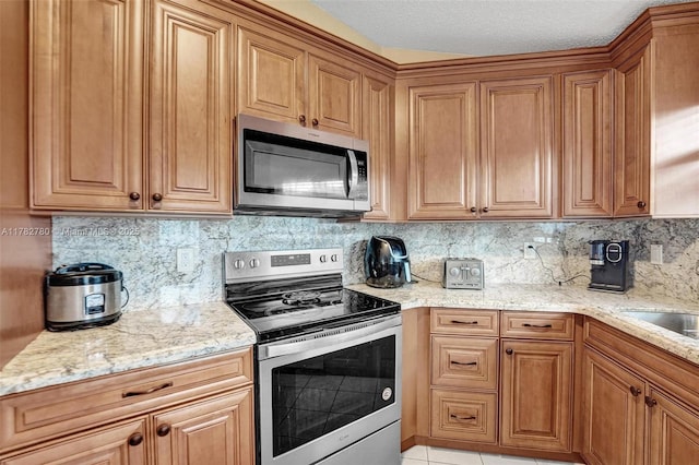 7324 NW 1st Pl, Plantation, FL 33317 - kitchen featuring brown cabinetry, decorative backsplash, appliances with stainless steel finishes, and light stone countertops