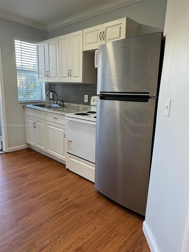 kitchen with electric range, freestanding refrigerator, crown molding, white cabinets, and a sink