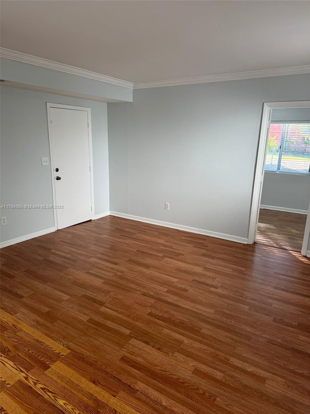 spare room featuring crown molding, baseboards, and wood finished floors