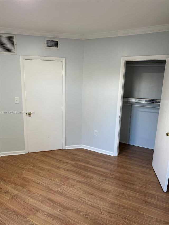 unfurnished bedroom with visible vents, crown molding, and wood finished floors