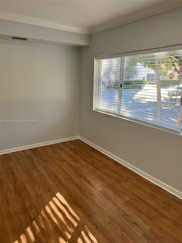 unfurnished room with dark wood-style flooring, ornamental molding, and baseboards