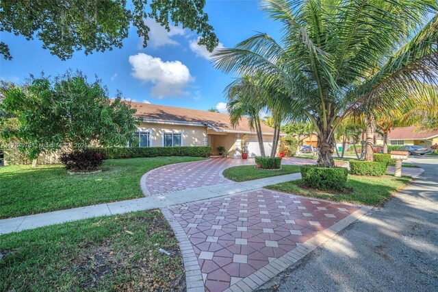 4991 NW 72nd Ter, Lauderhill, FL 33319 - mediterranean / spanish house with an attached garage, decorative driveway, a front lawn, and stucco siding