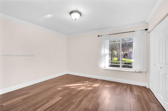 empty room with crown molding, baseboards, and wood finished floors