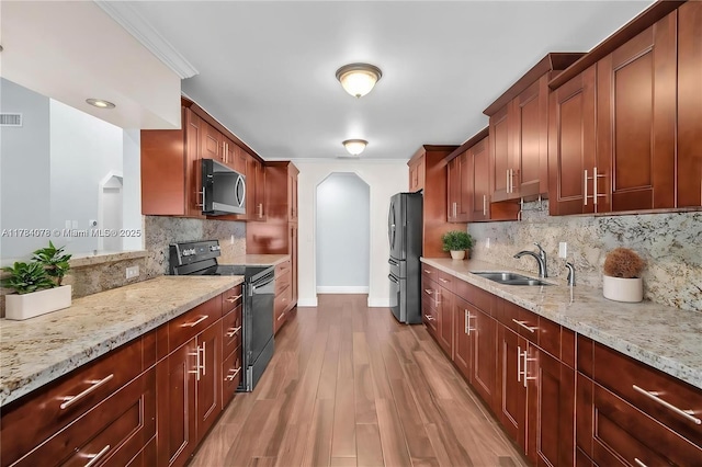 4991 NW 72nd Ter, Lauderhill, FL 33319 - kitchen featuring freestanding refrigerator, stainless steel microwave, arched walkways, a sink, and black / electric stove