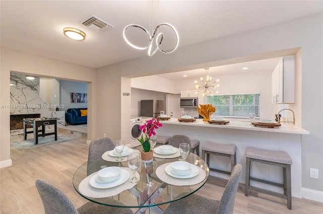 3313 SE 3rd St, Pompano Beach, FL 33062 - dining room with a chandelier, light wood-style flooring, washer / clothes dryer, and baseboards