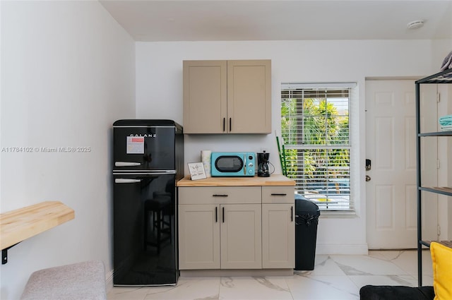 3313 SE 3rd St, Pompano Beach, FL 33062 - kitchen with freestanding refrigerator, wood counters, light marble finish flooring, baseboards, and gray cabinets