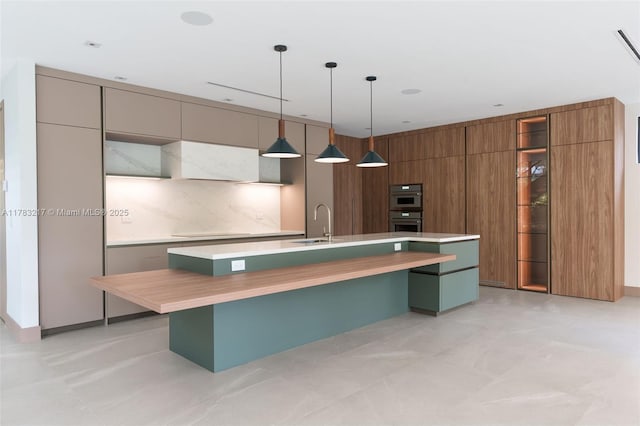 510 NE 52nd St, Miami, FL 33137 - kitchen featuring modern cabinets, light countertops, a sink, a kitchen island with sink, and stovetop
