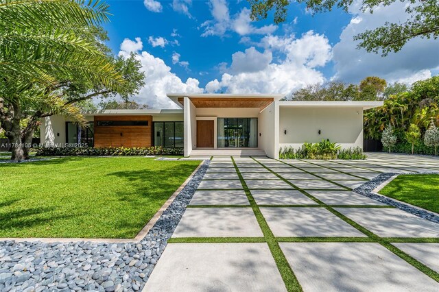 back of house featuring stucco siding and a yard