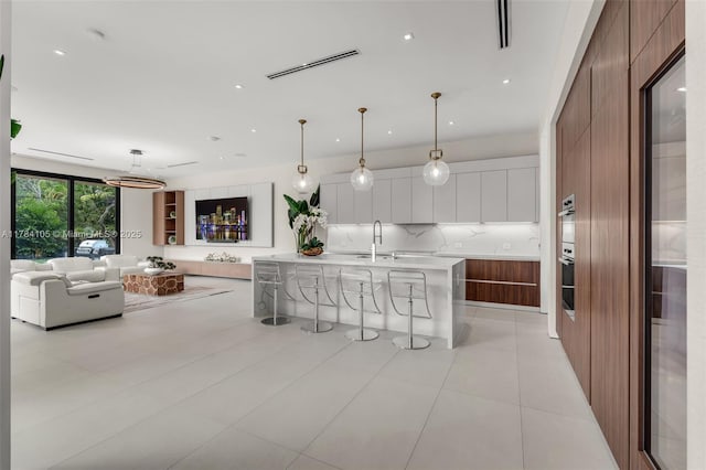 kitchen with modern cabinets, backsplash, a sink, light countertops, and white cabinetry