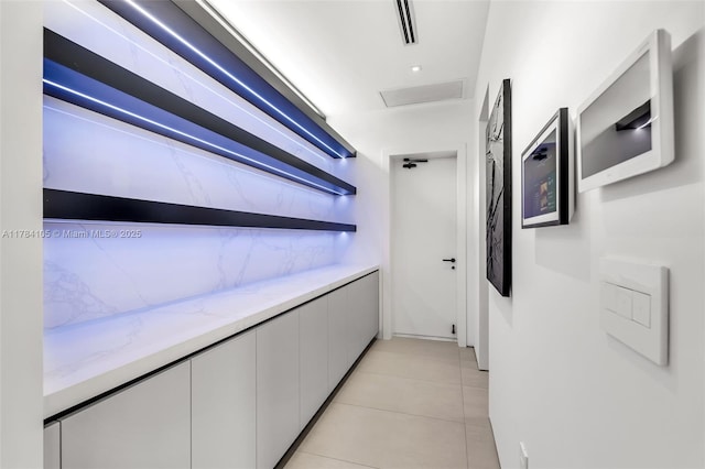 hallway with light tile patterned flooring and attic access