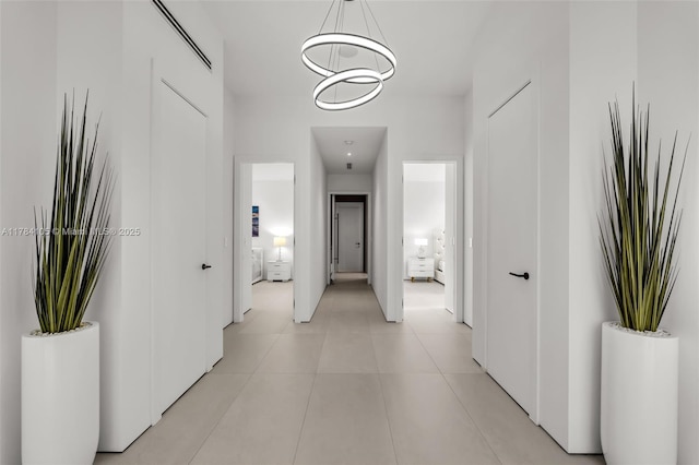 hall with light tile patterned floors and a chandelier