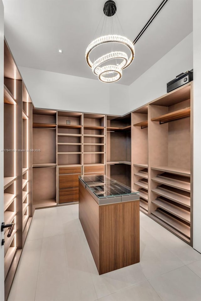 walk in closet with a chandelier and light tile patterned floors
