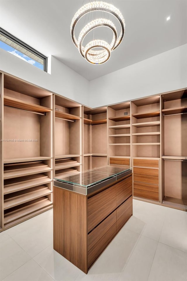 walk in closet with light tile patterned floors and a chandelier