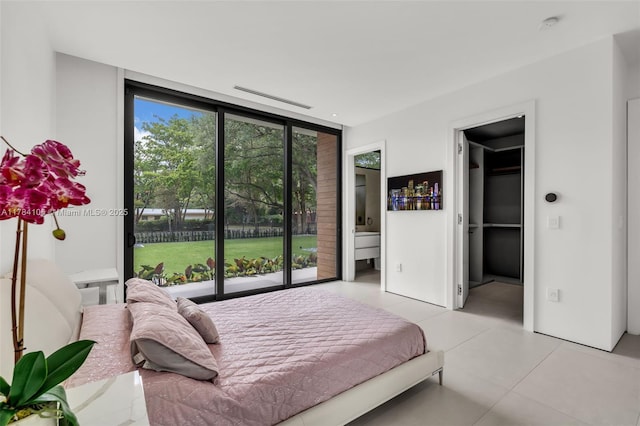 bedroom with expansive windows, light tile patterned floors, access to outside, and ensuite bath