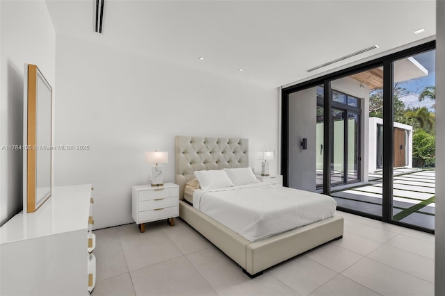 bedroom with access to exterior, light tile patterned floors, and a wall of windows