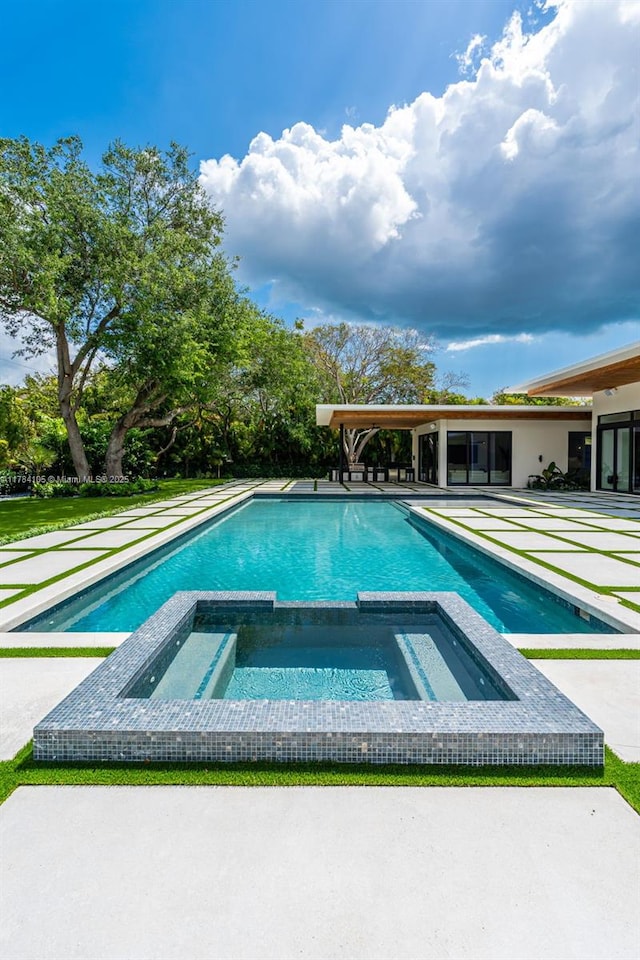view of swimming pool featuring a pool with connected hot tub and a patio
