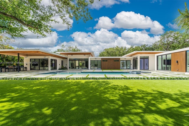 back of property featuring a lawn and an outdoor pool
