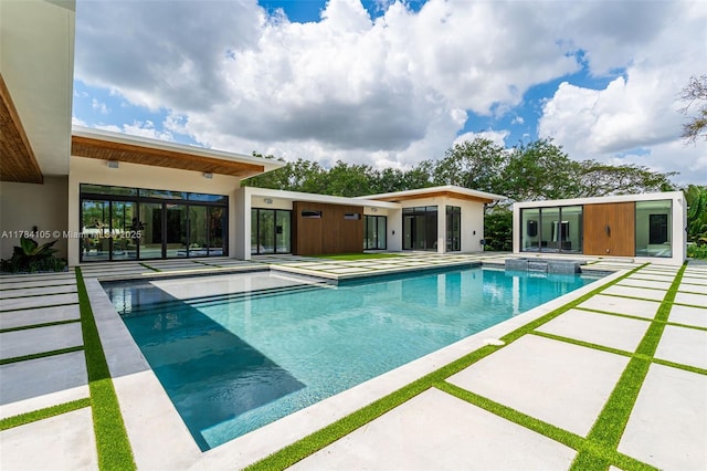 view of swimming pool with a patio area, a pool with connected hot tub, and an outbuilding