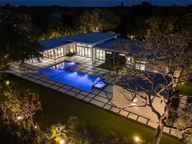 pool at twilight featuring a patio area