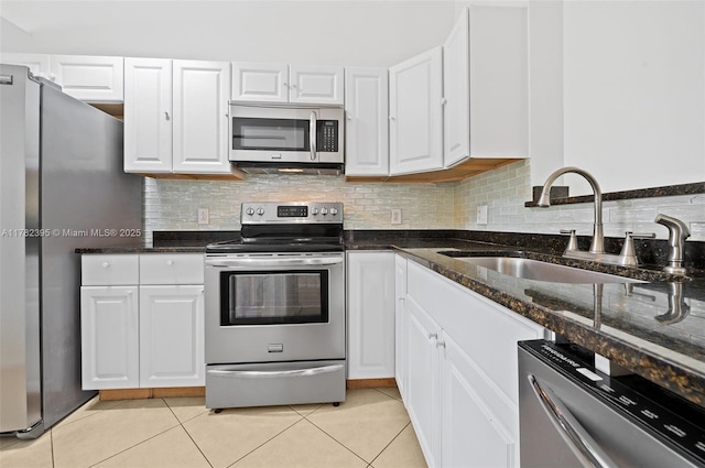 kitchen featuring tasteful backsplash, light tile patterned floors, white cabinetry, stainless steel appliances, and a sink
