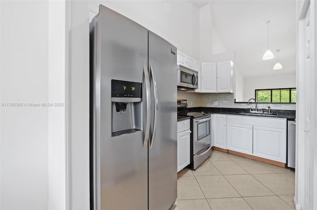 kitchen with a sink, dark countertops, white cabinetry, vaulted ceiling, and stainless steel appliances