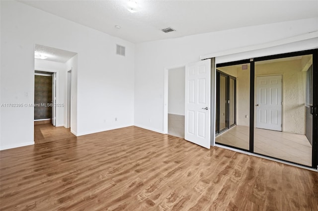 unfurnished bedroom featuring wood finished floors, baseboards, and visible vents