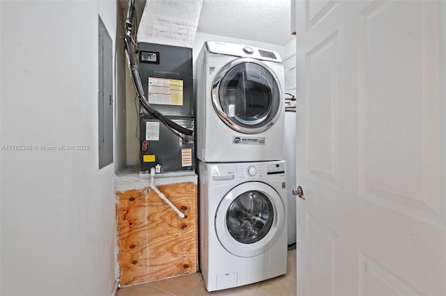 laundry area featuring stacked washing maching and dryer, laundry area, and light tile patterned flooring