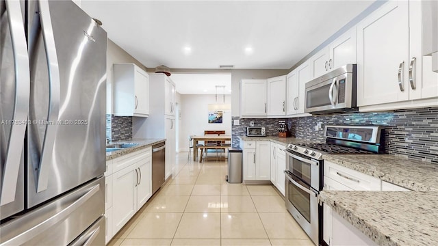 8435 SW 157th St, Palmetto Bay, FL 33157 - kitchen featuring light tile patterned floors, white cabinets, visible vents, stainless steel appliances, and backsplash