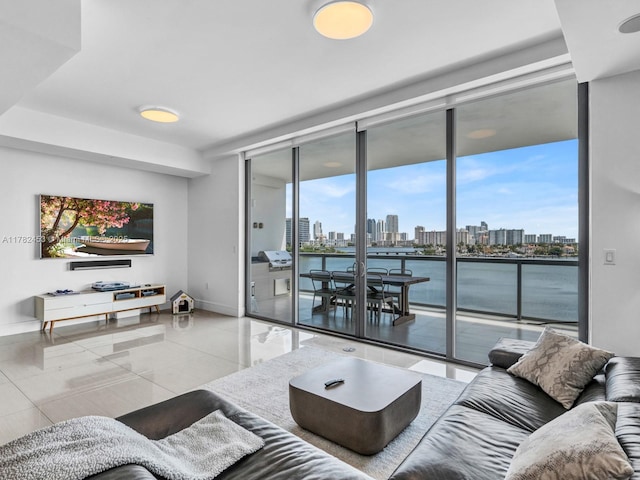 tiled living area featuring baseboards, expansive windows, and a water view