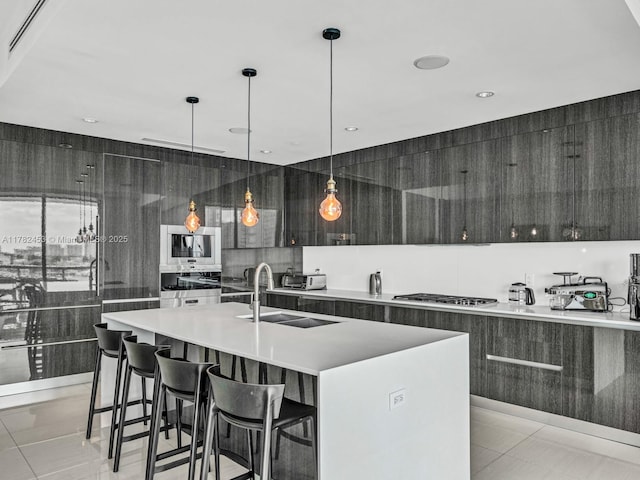 kitchen featuring a center island with sink, a sink, stainless steel gas stovetop, and modern cabinets