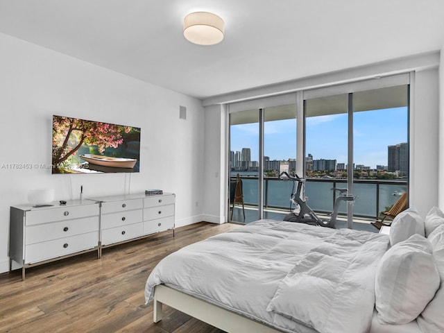 bedroom with access to outside, wood finished floors, baseboards, and expansive windows