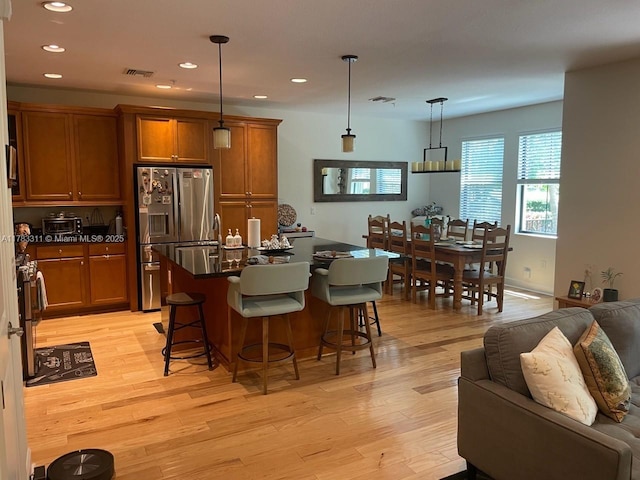 3142 NW 124th Way, Sunrise, FL 33323 - kitchen with stainless steel fridge with ice dispenser, brown cabinets, dark countertops, light wood finished floors, and recessed lighting