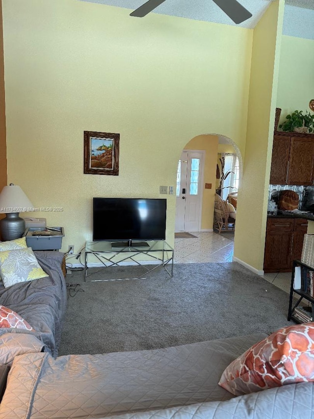 living room featuring arched walkways, baseboards, and a ceiling fan