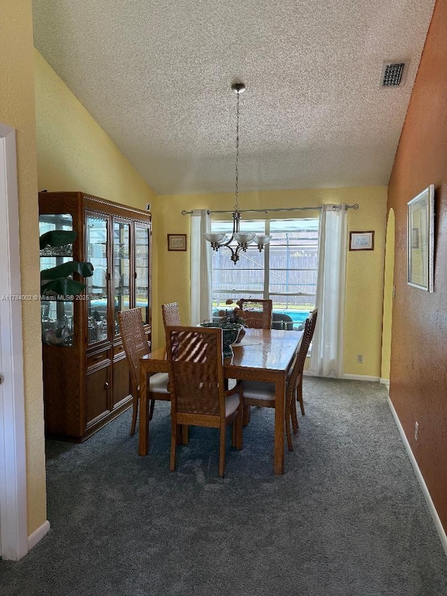 dining room featuring visible vents, dark carpet, a chandelier, a textured ceiling, and lofted ceiling