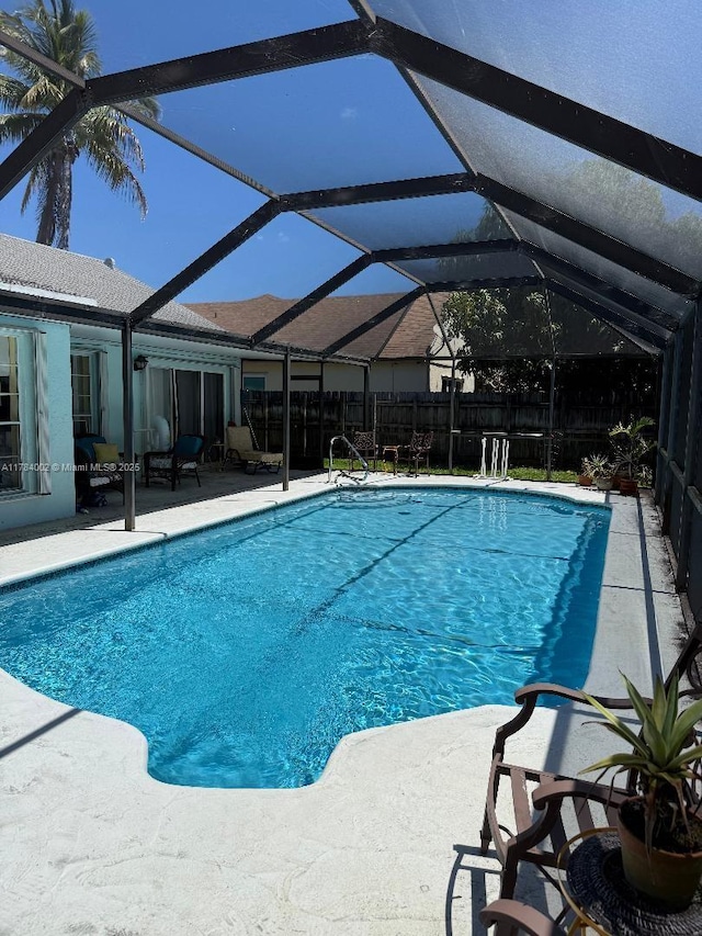 view of pool featuring fence, a fenced in pool, a patio, and glass enclosure